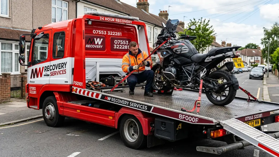 Flatbed recovery truck loading a motorcycle with wheel chock and tie-down straps